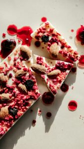Close-up of white chocolate pieces with almonds and berries, vibrant and artistic food photography.