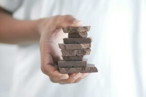Close-up of a hand holding a stack of chocolate bars with a soft background.