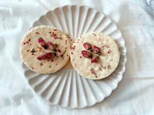 Delightful rose-decorated cheesecakes creatively arranged on a stylish white plate, perfect for gourmet food photography.