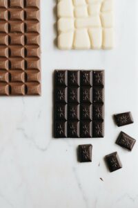 Assorted dark, milk, and white chocolate bars on a marble surface, perfect for dessert lovers.