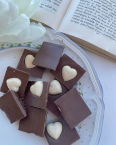 Heart-shaped chocolates arranged on a plate next to an open book for a cozy reading setting.
